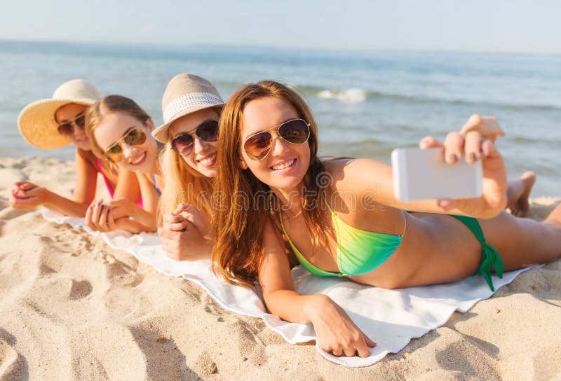 Gruppe lächelnde Frauen mit Smartphone auf Strand stockfotografie Gruppe lächelnde Frauen mit Smartphone auf Strand stockfotografie