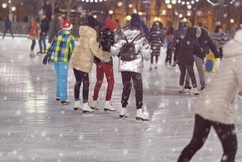 Gruppe Mädchen, die zurück zu uns eislaufen Freundineislauf im Stadtpark, schneebedeckter Abend Gesunder Winterbetrieb im Freien lizenzfreies stockfoto Gruppe Mädchen, die zurück zu uns eislaufen Freundineislauf im Stadtpark, schneebedeckter Abend Gesunder Winterbetrieb im Freien lizenzfreies stockfoto