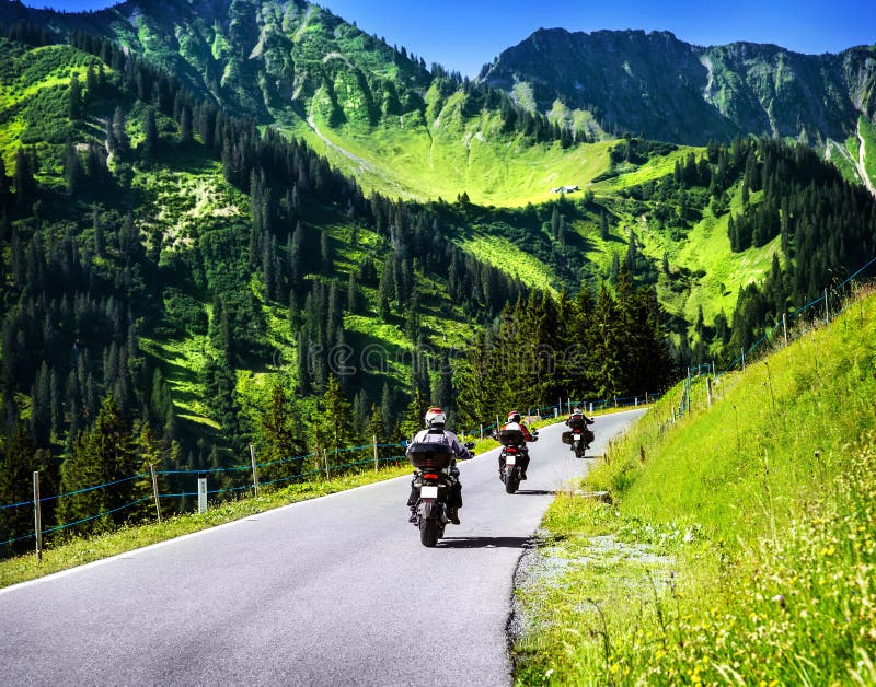 Group of travelling bikers in Alpine mountains, riding on mountainous highway, extreme lifestyle, spring travel and adventure concept. Group of travelling bikers in Alpine mountains, riding on mountainous highway, extreme lifestyle, spring travel and adventure concept