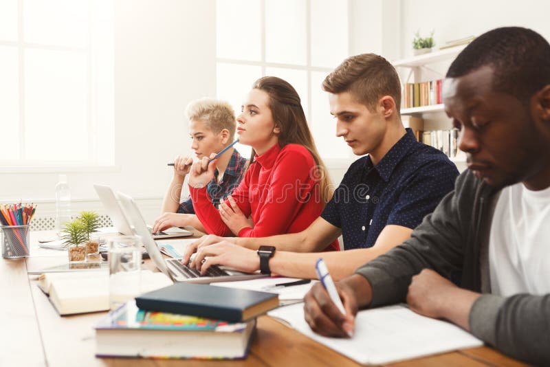 Gruppe verschiedene Studenten, die am Holztisch studieren lizenzfreie stockbilder Gruppe verschiedene Studenten, die am Holztisch studieren lizenzfreie stockbilder