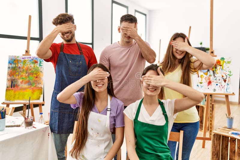 Group of five hispanic artists at art studio smiling and laughing with hand on face covering eyes for surprise. blind concept. Group of five hispanic artists at art studio smiling and laughing with hand on face covering eyes for surprise. blind concept