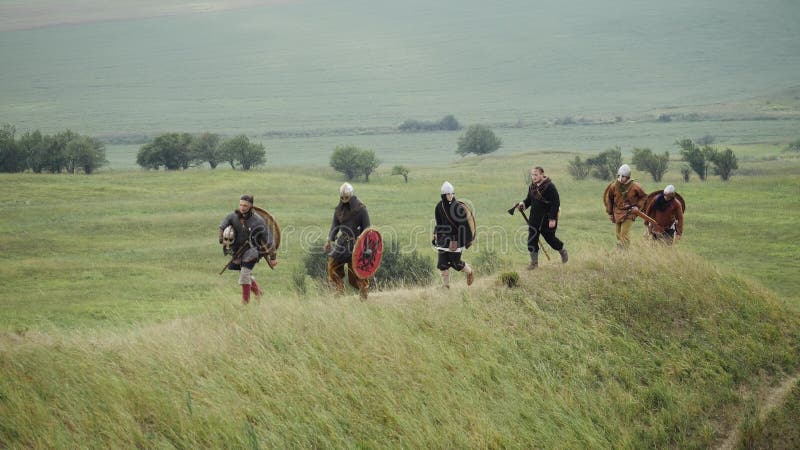 Gruppe von Viking mit Schildern gehend vorwärts auf die Wiese