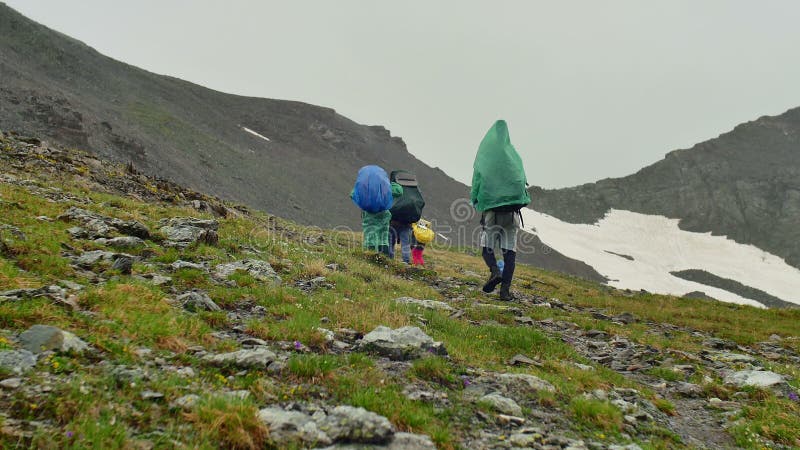 Gruppen av turister går under regnet i höga snöig berg
