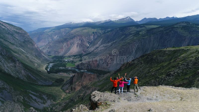 Gruppen av vänner är lycklig, att klättrat till överkanten berget De kramar och hoppar Se in i avståndet med baksida