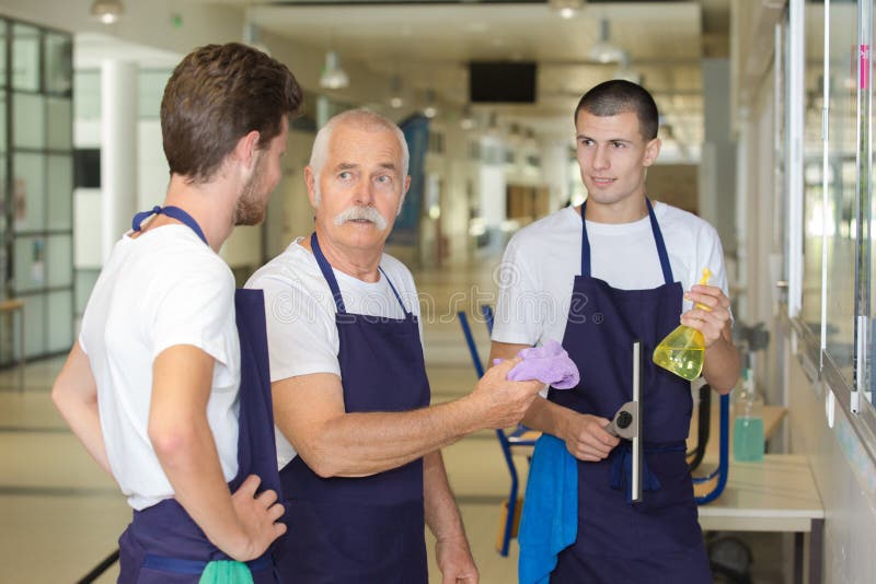 Gruppenberufsbüroreiniger, die Bruch während der Arbeit haben lizenzfreies stockbild Gruppenberufsbüroreiniger, die Bruch während der Arbeit haben lizenzfreies stockbild