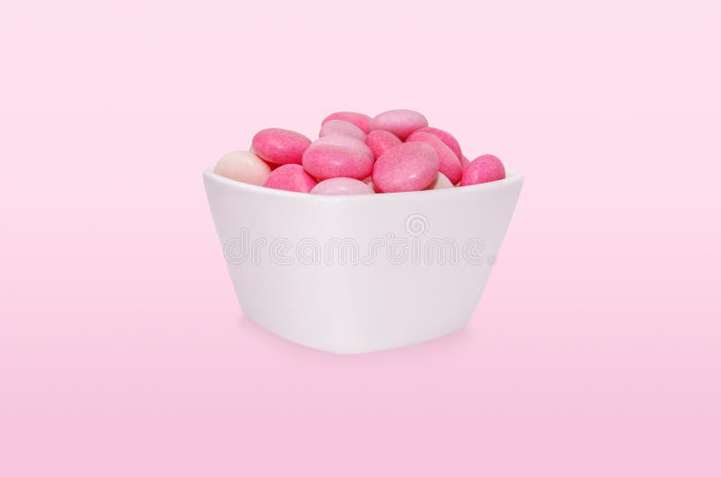 Gruppenrosa lässt Süßwaren in der Schale fallen, die auf rosa Hintergrund befindet