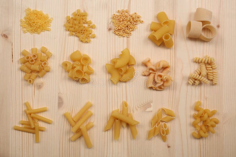 Grupper av olika sorter av torr okokt pasta på en trätabell fotografering för bildbyråer Grupper av olika sorter av torr okokt pasta på en trätabell fotografering för bildbyråer