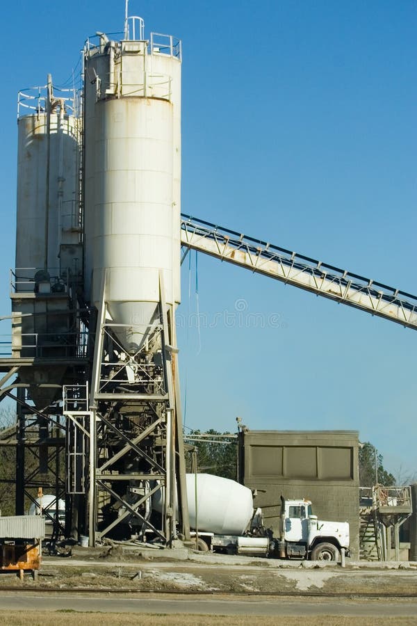 A photo of a concrete truck at a concrete batch plant. A photo of a concrete truck at a concrete batch plant