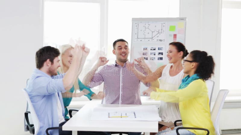 Gruppo creativo felice che celebra vittoria in ufficio