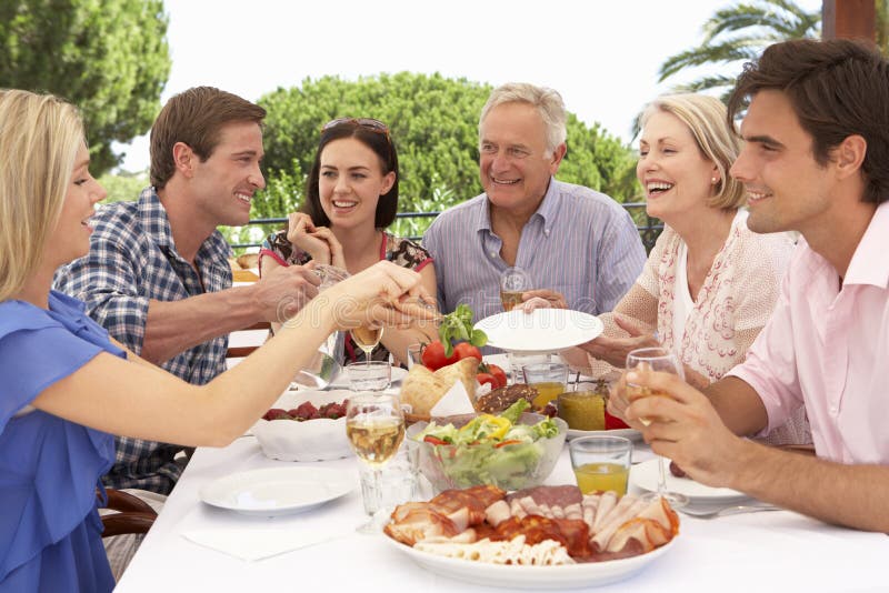 Gruppo della famiglia allargata che gode insieme del pasto all'aperto immagine stock Gruppo della famiglia allargata che gode insieme del pasto all'aperto immagine stock