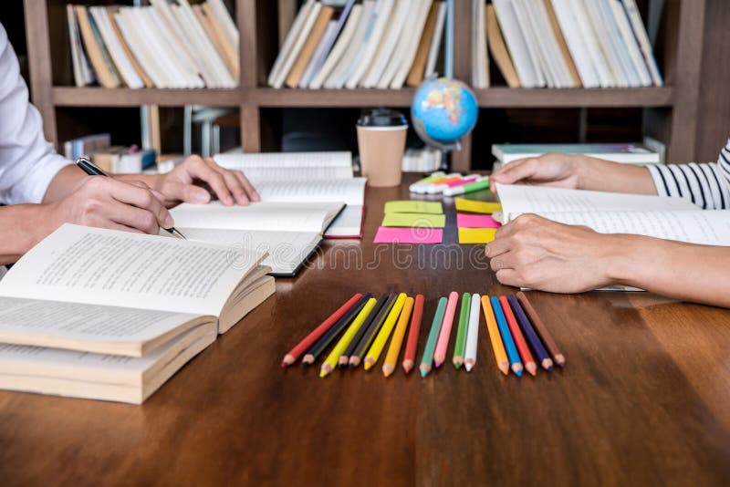 Gruppo dello studente di college o della High School che si siede allo scrittorio in biblioteca che studia e che legge, facendo p fotografie stock Gruppo dello studente di college o della High School che si siede allo scrittorio in biblioteca che studia e che legge, facendo p fotografie stock