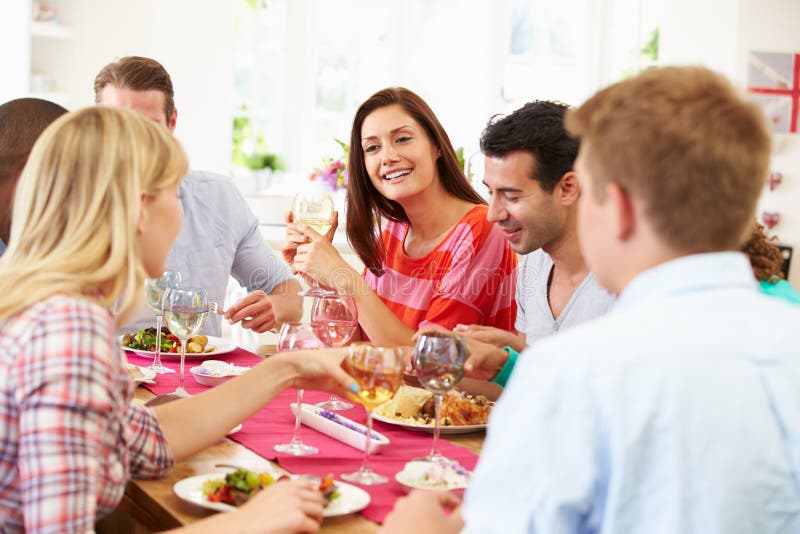 Gruppo di amici che si siedono intorno alla Tabella cenando partito immagine stock libera da diritti Gruppo di amici che si siedono intorno alla Tabella cenando partito immagine stock libera da diritti