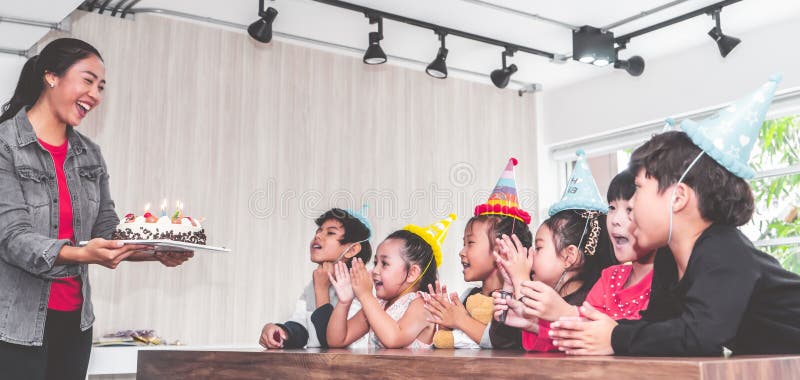 Gruppo di bambini che soffiano torta di compleanno nella festa di compleanno che canta buon compleanno fotografie stock Gruppo di bambini che soffiano torta di compleanno nella festa di compleanno che canta buon compleanno fotografie stock