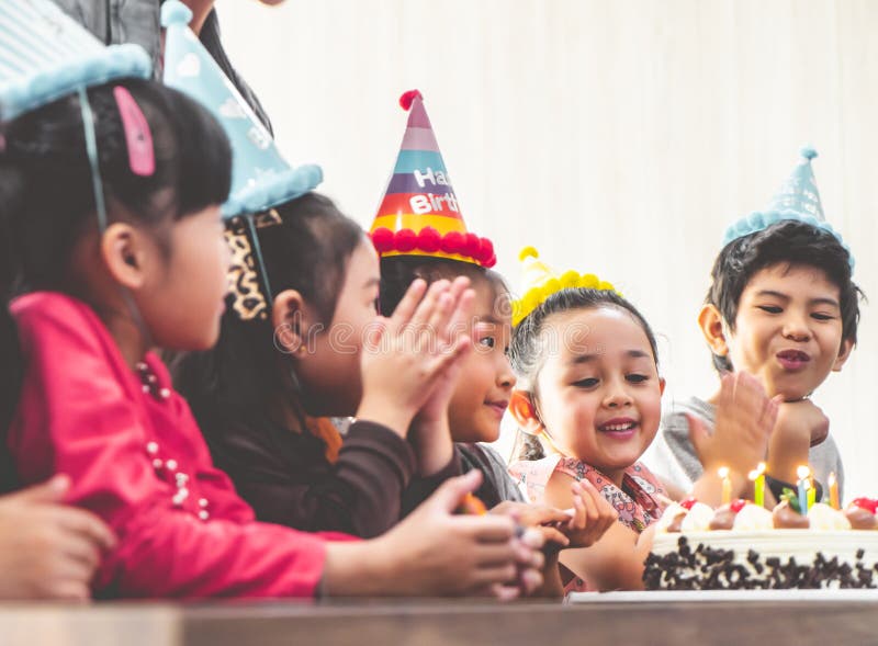 Gruppo di bambini che soffiano torta di compleanno nella festa di compleanno che canta buon compleanno fotografie stock Gruppo di bambini che soffiano torta di compleanno nella festa di compleanno che canta buon compleanno fotografie stock