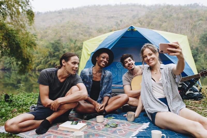 Group of young adult friends in camp site taking a group selfie outdoors recreational leisure, freedom and adventure concept. Group of young adult friends in camp site taking a group selfie outdoors recreational leisure, freedom and adventure concept