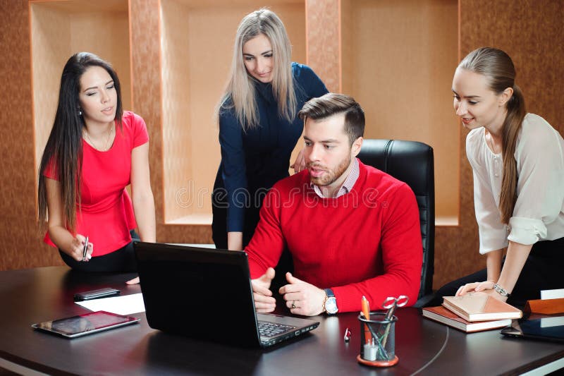 Gruppo di giovani colleghi che per mezzo del computer portatile all'ufficio immagine stock Gruppo di giovani colleghi che per mezzo del computer portatile all'ufficio immagine stock
