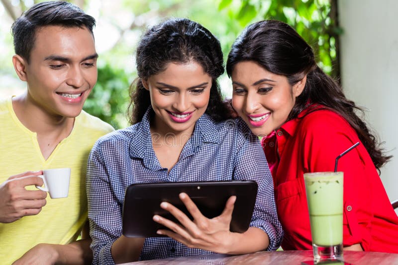 Gruppo di giovani indiani che esaminano il computer della compressa immagine stock libera da diritti Gruppo di giovani indiani che esaminano il computer della compressa immagine stock libera da diritti