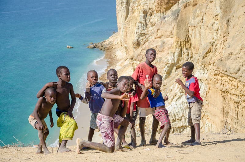 Gruppo di giovani ragazzi africani che posano davanti alla linea ed all'oceano spettacolari della costa del deserto alla Praia da immagine stock libera da diritti Gruppo di giovani ragazzi africani che posano davanti alla linea ed all'oceano spettacolari della costa del deserto alla Praia da immagine stock libera da diritti