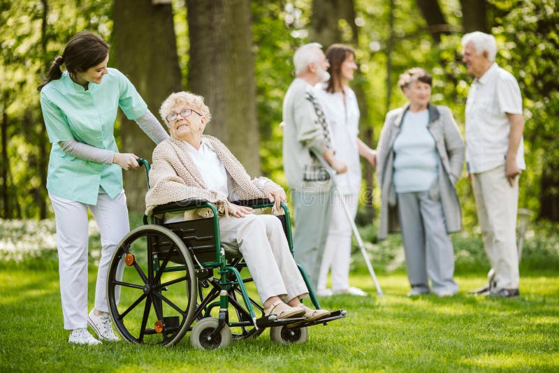 Group of senior patients with caregiver in the garden of nursing home. Group of senior patients with caregiver in the garden of nursing home