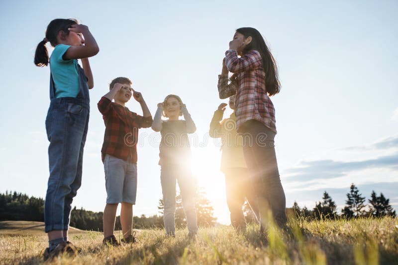 Portrait of group of school children standing on field trip in nature at sunset, playing. Portrait of group of school children standing on field trip in nature at sunset, playing.