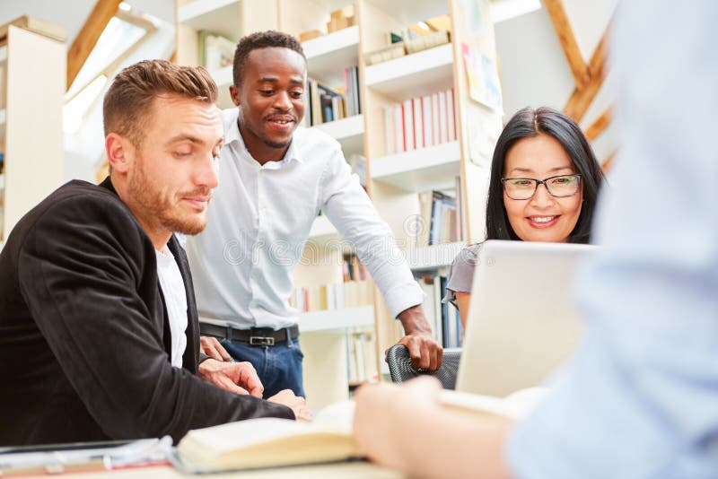 Gruppo di studenti nella biblioteca mentre imparando immagine stock libera da diritti Gruppo di studenti nella biblioteca mentre imparando immagine stock libera da diritti