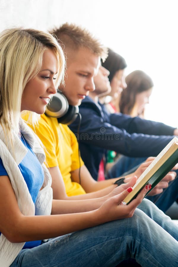 Gruppo di studenti sui libri di lettura della rottura e sugli smartphones usando fotografia stock libera da diritti Gruppo di studenti sui libri di lettura della rottura e sugli smartphones usando fotografia stock libera da diritti