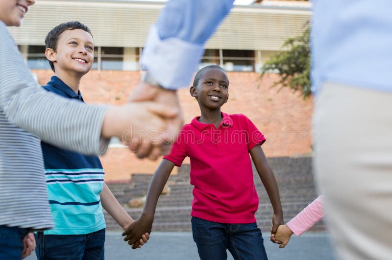 Happy multiethnic kids holding hands together outside the school. Group of happy children smiling and listening to game rules. Group of pupils playing ring around the rosie. Happy multiethnic kids holding hands together outside the school. Group of happy children smiling and listening to game rules. Group of pupils playing ring around the rosie.