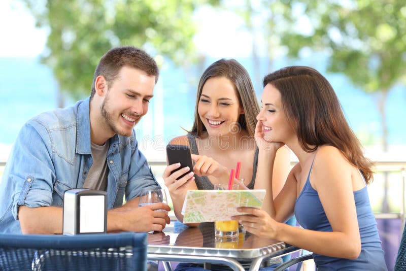 Gruppo di turisti che controllano telefono e mappa sulla vacanza fotografia stock Gruppo di turisti che controllano telefono e mappa sulla vacanza fotografia stock