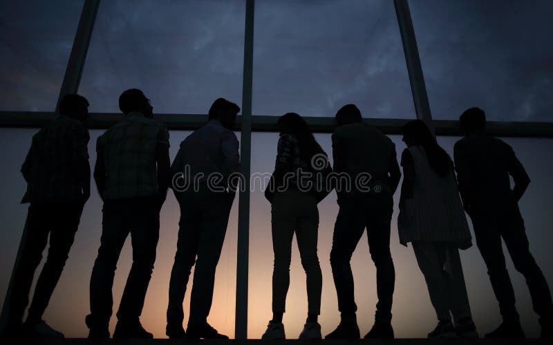 Gruppo moderno di affari che sta vicino ad una grande finestra immagini stock Gruppo moderno di affari che sta vicino ad una grande finestra immagini stock
