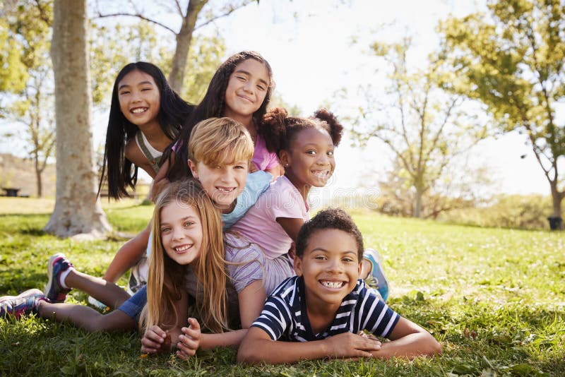 gruppo Multi-etnico di bambini che si trovano su a vicenda in un parco