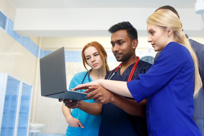 Gruppo multirazziale di giovani medici che lavorano al computer portatile in ufficio medico fotografie stock libere da diritti Gruppo multirazziale di giovani medici che lavorano al computer portatile in ufficio medico fotografie stock libere da diritti
