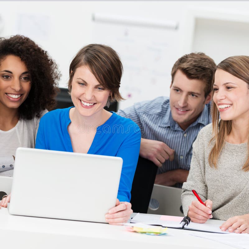 Gruppo sorridente di affari raggruppato intorno ad un computer portatile immagini stock libere da diritti Gruppo sorridente di affari raggruppato intorno ad un computer portatile immagini stock libere da diritti