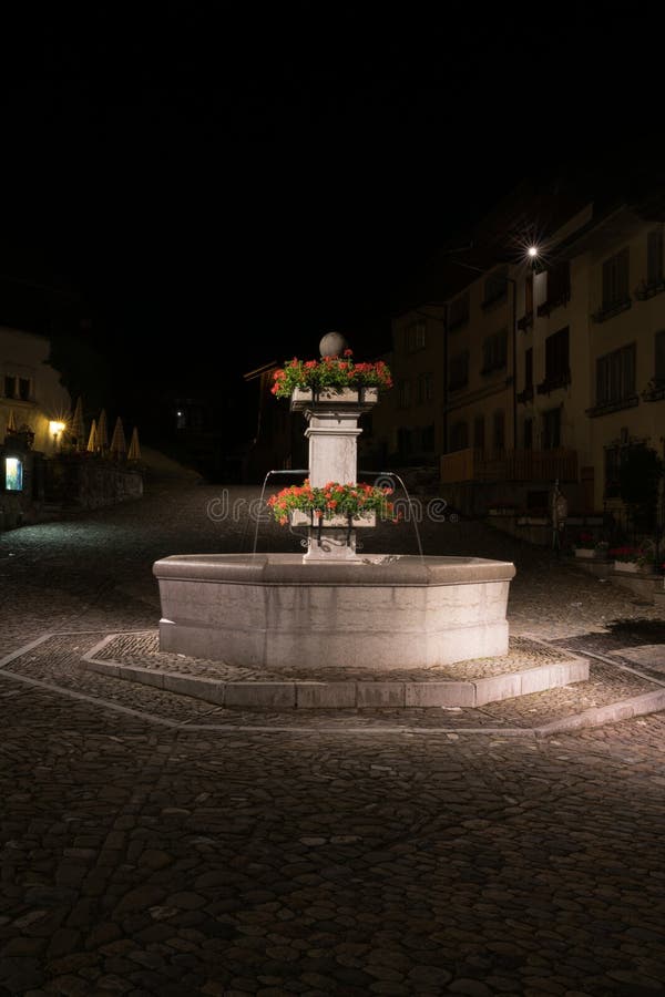Gruyeres, VD/Suiza - 31 de mayo de 2019: el pueblo medieval histórico de Gruyeres con la fuente cuadrada del pueblo en la noche foto de archivo Gruyeres, VD/Suiza - 31 de mayo de 2019: el pueblo medieval histórico de Gruyeres con la fuente cuadrada del pueblo en la noche foto de archivo