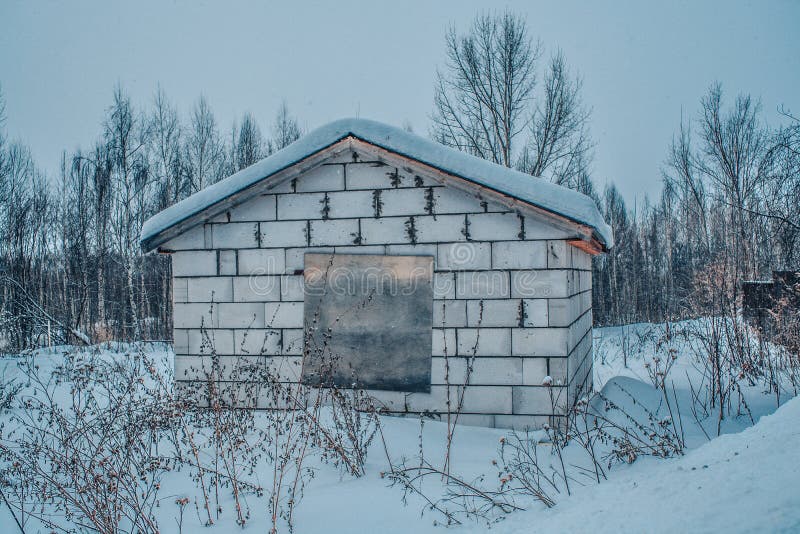 Grå betongvägg för gammal ladugård med snö på taket och som stiger ombord upp fönstret arkivfoton Grå betongvägg för gammal ladugård med snö på taket och som stiger ombord upp fönstret arkivfoton