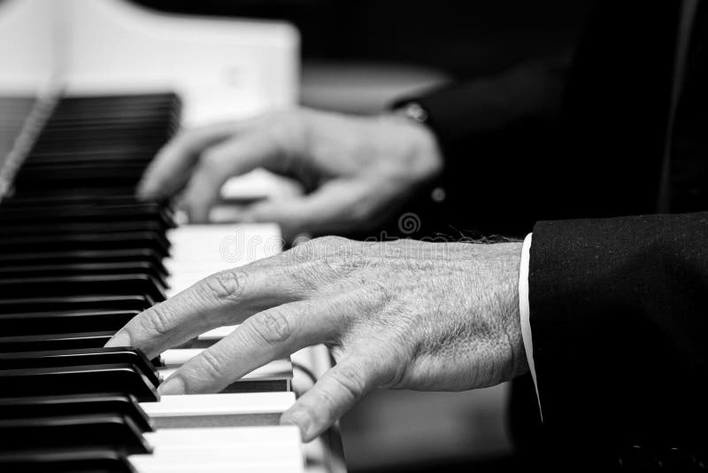 Gråskalebild av gamla händer som spelar piano arkivfoto