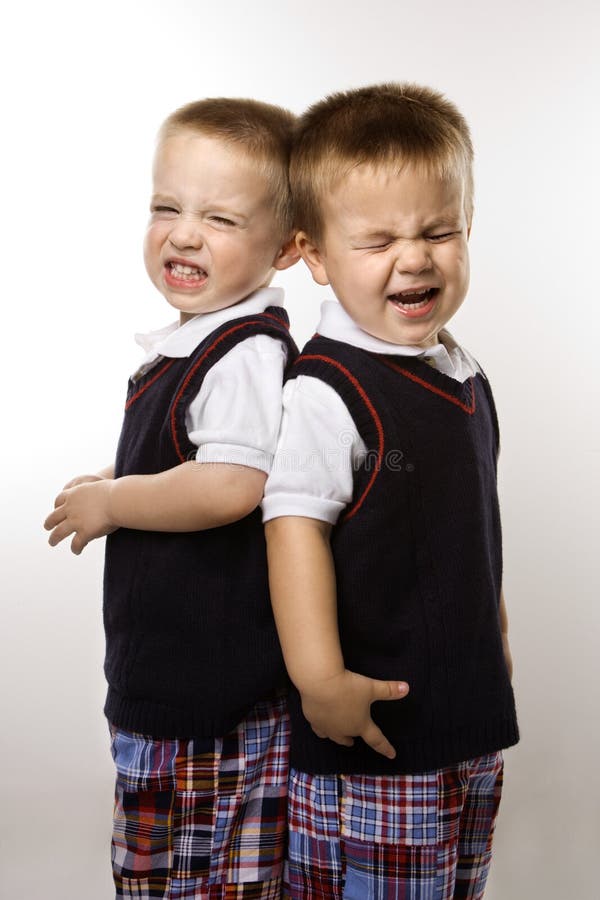 Caucasian twin boys crying standing against white background. Caucasian twin boys crying standing against white background.