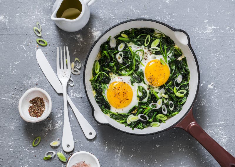 Grön shakshuka Stekte ägg med nya spenat, ramson, purjolök i en panna på en grå bakgrund royaltyfri fotografi Grön shakshuka Stekte ägg med nya spenat, ramson, purjolök i en panna på en grå bakgrund royaltyfri fotografi