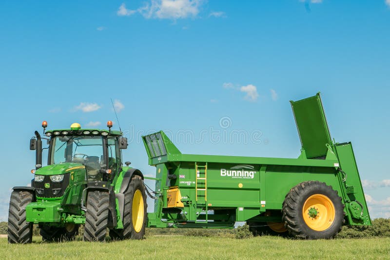 Gröna en John Deere traktorer som drar bunning gyttjaspreaders arkivfoto Gröna en John Deere traktorer som drar bunning gyttjaspreaders arkivfoto