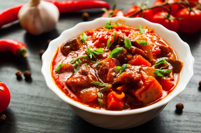 Grönsakrague med aubergine, peppar, tomaten och moroten i den vita bunken på mörk träbakgrund royaltyfria bilder Grönsakrague med aubergine, peppar, tomaten och moroten i den vita bunken på mörk träbakgrund royaltyfria bilder