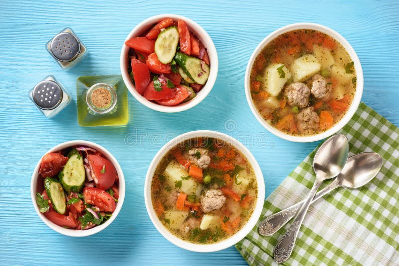 Grönsaksoppa med köttbullar och tomatsallad royaltyfri bild Grönsaksoppa med köttbullar och tomatsallad royaltyfri bild