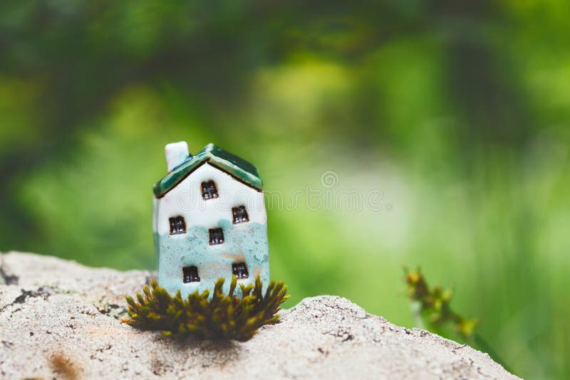 Grönt litet hus på solig naturbakgrund arkivbild