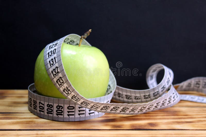 Grönt äpple som vrids med ett mäta band arkivfoton Grönt äpple som vrids med ett mäta band arkivfoton