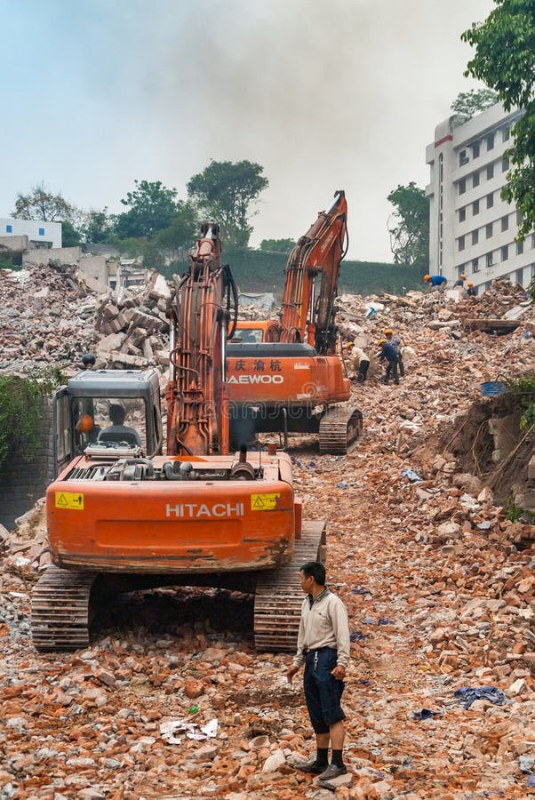 Chongqing, China - May 9, 2010: Downtown, off Peoples Square. Red Daewoo and Hitachi demolition craned on top of pile of stone rubble. Workers present. Chongqing, China - May 9, 2010: Downtown, off Peoples Square. Red Daewoo and Hitachi demolition craned on top of pile of stone rubble. Workers present