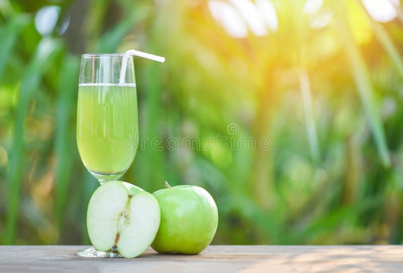 Grüner Apfelsaft im Glas und in der Scheibenapfelfrucht mit Naturgrün-Sommerhintergrund stockbild