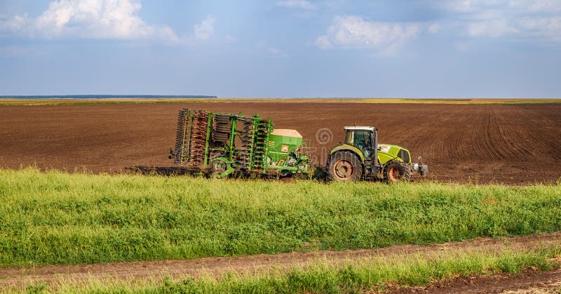 Grüner Traktor der Landwirtschaft, der Samen sät und Feld am späten Nachmittag kultiviert stockfotos Grüner Traktor der Landwirtschaft, der Samen sät und Feld am späten Nachmittag kultiviert stockfotos
