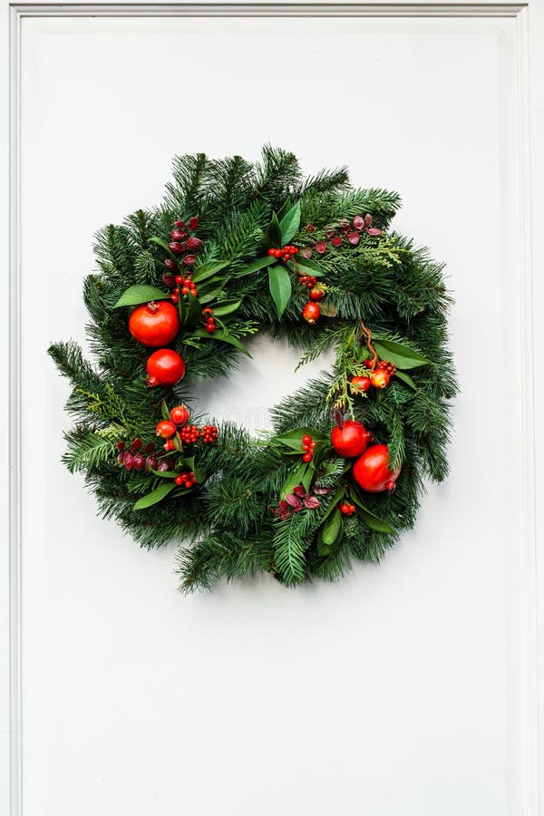 Grüner Weihnachtskranz mit Granatapfel und roten Beeren auf weißer Tür stockfoto Grüner Weihnachtskranz mit Granatapfel und roten Beeren auf weißer Tür stockfoto