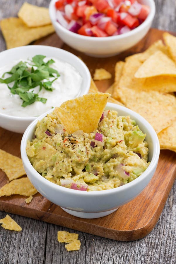 Guacamole Sauce, Tomato Salsa and Corn Chips on a Wooden Board Stock