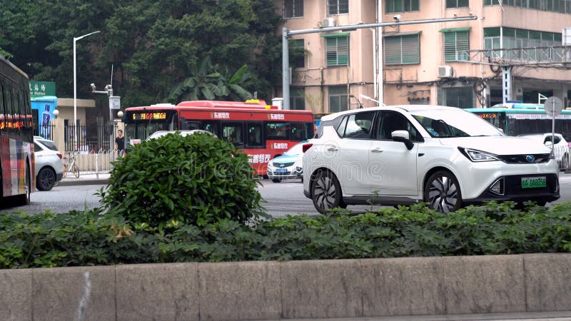 Guangzhou, China - May, 2019: View of roadway with cars and buses in city. Media. Turn city road with flow of transport in China. Green bushes along city road in China. Guangzhou, China - May, 2019: View of roadway with cars and buses in city. Media. Turn city road with flow of transport in China. Green bushes along city road in China.