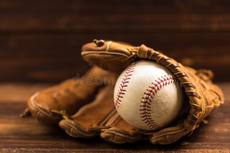 Guante y bola de cuero de béisbol en un banco de madera imágenes de archivo libres de regalías Guante y bola de cuero de béisbol en un banco de madera imágenes de archivo libres de regalías