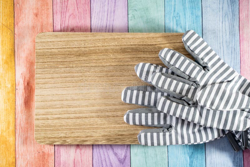 Guantes que cultivan un huerto rayados en un tablón de madera, sobre un fondo de madera en colores pastel del arco iris Útil pa fotos de archivo libres de regalías Guantes que cultivan un huerto rayados en un tablón de madera, sobre un fondo de madera en colores pastel del arco iris Útil pa fotos de archivo libres de regalías